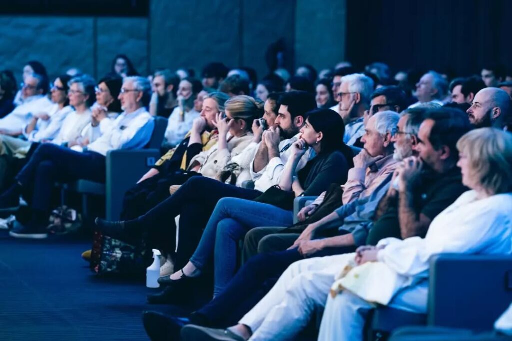 Pubblico seduto nelle poltrone della sala che segue l'evento.