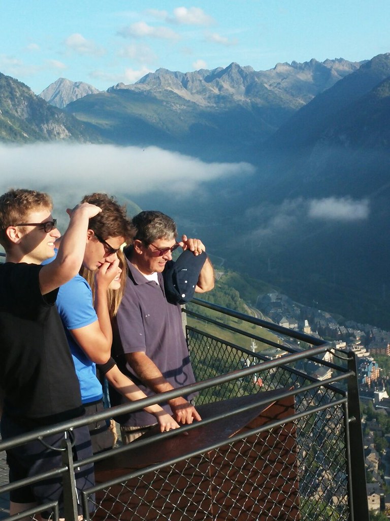 Un grupo de jóvenes y un hombre adulto en un mirador de montaña contemplan un valle cubierto de nubes