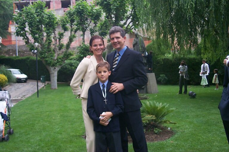 Marcos Pou de niño, con traje y cruz al cuello el día de su primera comunión, junto a sus padres en un jardín