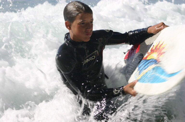 Marcos Pou, con traje de neopreno y tabla de bodyboard, entre la espuma de las olas en el mar