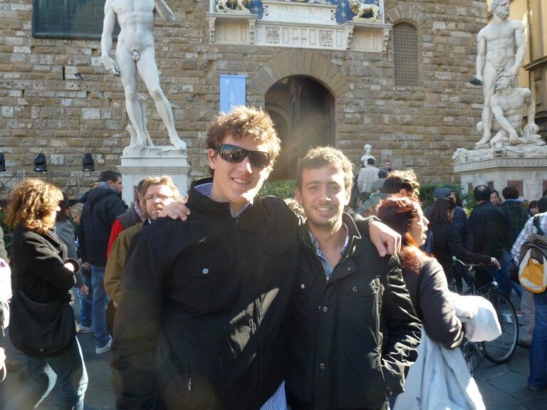 Marcos Pou abrazado a un amigo ante el Palazzo Vecchio de Florencia, entre turistas y esculturas