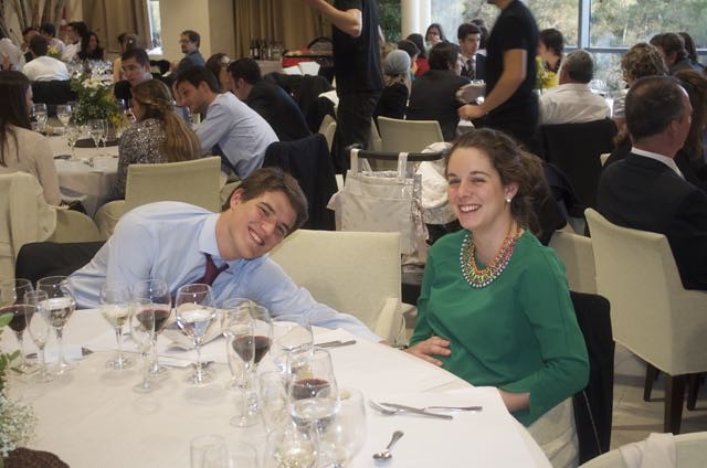 Marcos Pou sonriente junto a una joven vestida de verde en una mesa de banquete durante una celebración