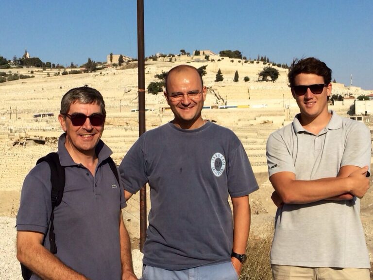 Tres peregrinos sonrientes posan al sol ante la ladera del Monte de los Olivos, en Jerusalén