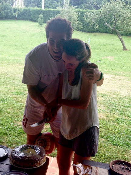 Marcos Pou abrazando y riendo con una joven en un jardín, junto a una mesa con tartas
