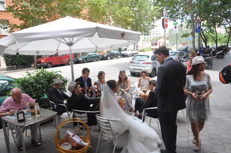 Una novia y varios invitados de boda reunidos en la terraza de un bar en una calle de Barcelona