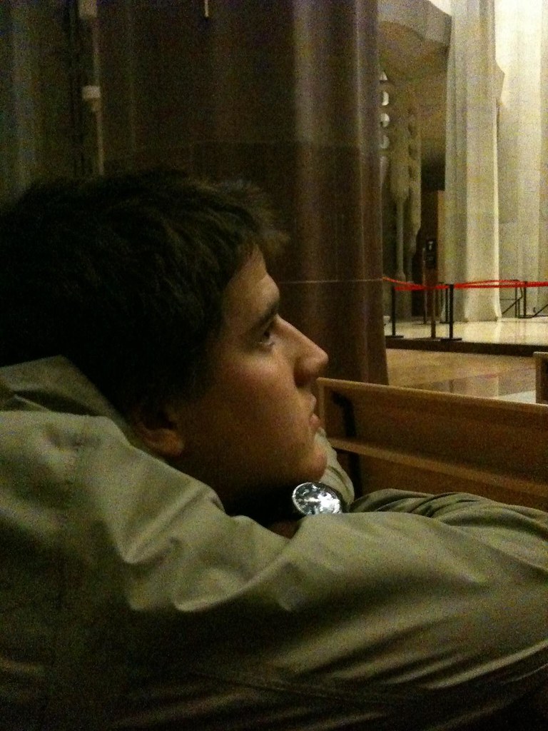 Marcos Pou seated on a pew inside a church, in profile and gazing upwards